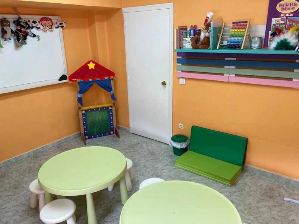 Aula de infantil de Brigsol con mesas verdes y teatrillo